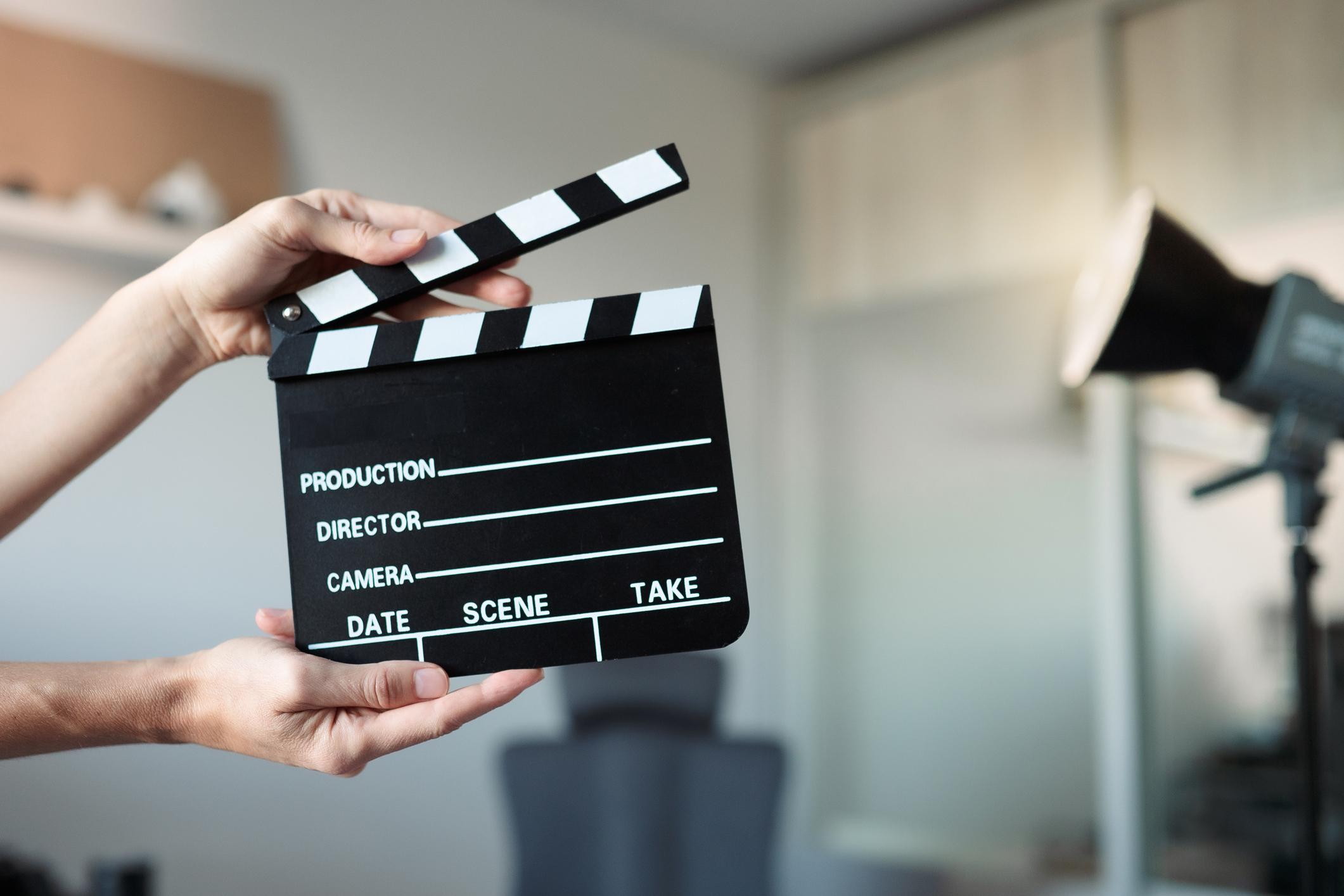 Clapper board resting in front of soft bokeh lights for video script work.